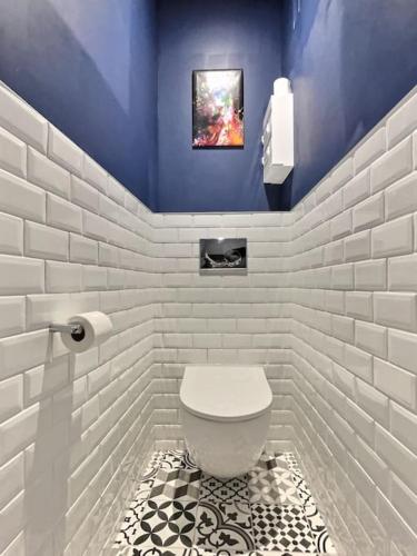 La salle de bains est pourvue de toilettes blanches et d'un mur bleu. dans l'établissement Au Jasmin de Miss K, à Bourg-en-Bresse