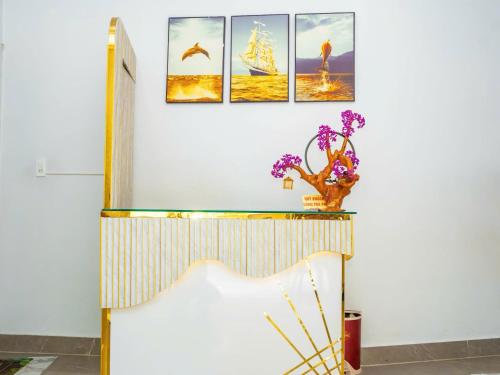 a room with a table with three paintings on the wall at Duc Duy Hotel Cat Ba in Cat Ba