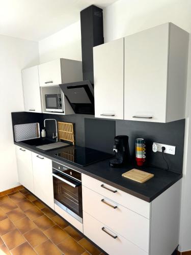 une cuisine avec des armoires blanches et un comptoir noir dans l'établissement La Douceur des Alpilles, à Saint-Rémy-de-Provence