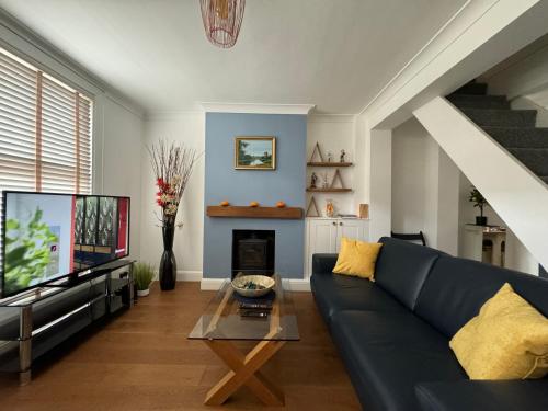 a living room with a blue couch and a tv at Spacious 3 Bed House Free Parking Maidstone in Maidstone