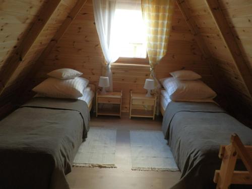 2 Betten in einem Dachzimmer mit Fenster in der Unterkunft Cicha Przystań in Sasino