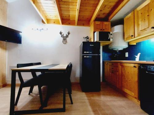 Il comprend une cuisine équipée d'une table et d'un réfrigérateur noir. dans l'établissement LE COSY à Aime La Plagne, à Aime La Plagne