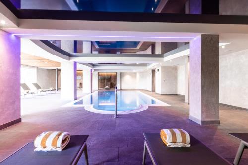 a swimming pool in a building with two chairs at Hotel Zum Löwen - Al Leone in Meltina