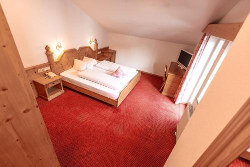 a bedroom with a bed and a red carpet at Hotel Zum Löwen - Al Leone in Meltina