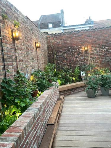 un mur en briques avec des plantes sur une terrasse en bois dans l'établissement Beau Studio tout neuf proche de Lille, à Houplines