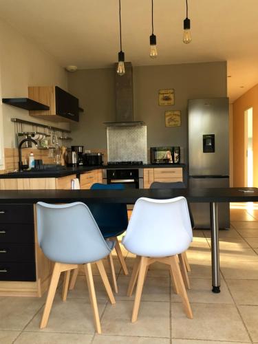 une cuisine avec une table noire et deux chaises blanches dans l'établissement Maison de campagne meublée, à Issac
