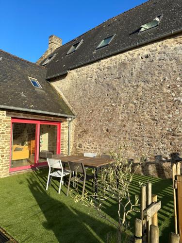 a patio with a table and chairs in front of a building at Maison entre Rennes et St-Malo in Saint-Pierre-de-Plesguen