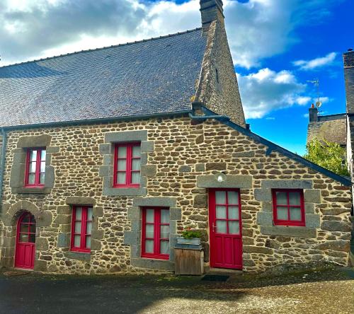 a stone building with red windows and a roof at Maison entre Rennes et St-Malo in Saint-Pierre-de-Plesguen