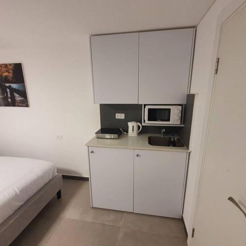 a bedroom with a bed and a white cabinet with a microwave at Ryo 17 דירה במלון בוטיק 2 דקות מטיילת בת ים in Bat Yam