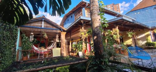 a house with a palm tree in front of it at Yolo Hostel Medellin in Medellín