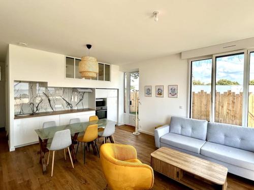 una sala de estar con un sofá, una mesa y sillas en Bel Appartement face mer, en Billiers