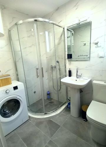 a bathroom with a shower and a washing machine at Vrnjački Kos in Vrnjačka Banja