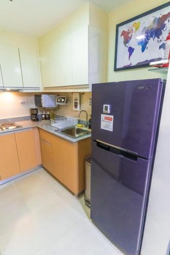 a kitchen with a purple refrigerator and a sink at Paladium Iloilo Smart Home Condo in Iloilo City