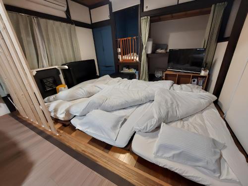 a large bed with white sheets and pillows at つきびとはうす in Satte