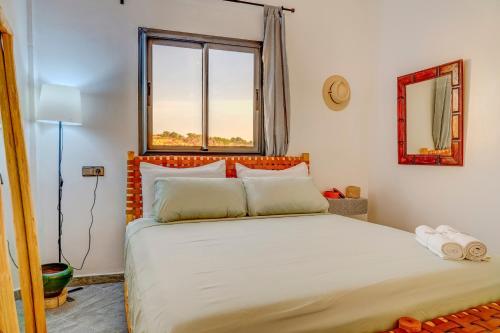 a bedroom with a large white bed with a window at Muse in Zaouit Louda