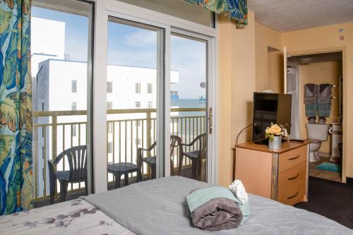 a bedroom with a balcony with a bed and a television at Baywatch Resort in Myrtle Beach
