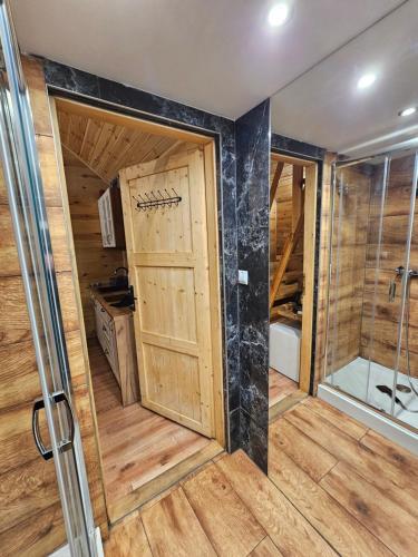 a bathroom with a shower and a wooden door at Roztoczański Domek in Zwierzyniec