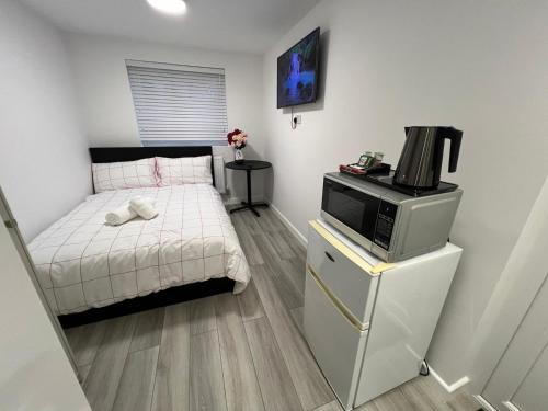 a small bedroom with a bed and a microwave at Guest Suite in Milton Keynes in Milton Keynes