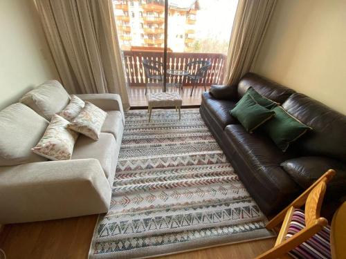 a living room with a leather couch and a rug at Nevados de chillan , edificio los coigues in Nevados de Chillan