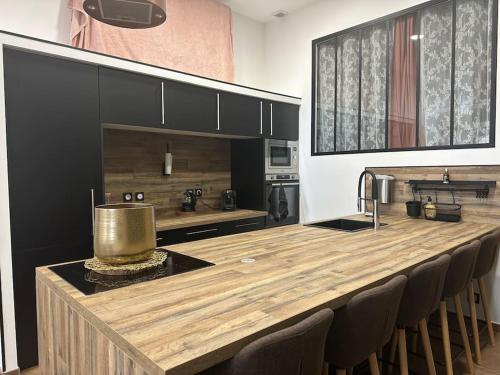 une cuisine avec un grand comptoir en bois et des chaises dans l'établissement Appartement 2 personnes, à Châteauneuf-de-Gadagne