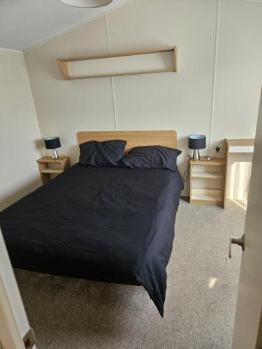 a bedroom with a black bed and two night stands at Trecco bay birch in Newton