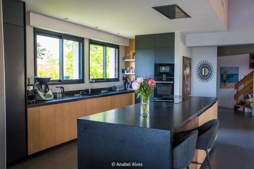 - une cuisine avec un comptoir orné d'un vase de fleurs dans l'établissement Villa 250 m2, piscine à 10 minutes de Toulouse, à Montrabé