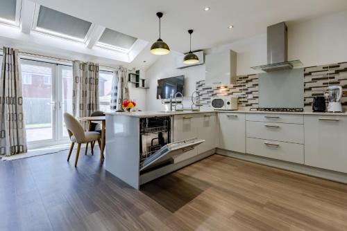 a kitchen with white cabinets and a table and chairs at Luxurious 2 Bed House near Birmingham in Bilston