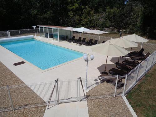 - une piscine avec des parasols et des chaises longues dans l'établissement Les Mémis, à Bourdeilles