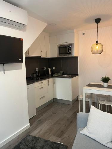 a small kitchen with white cabinets and a table at H I Alojamento in Manteigas