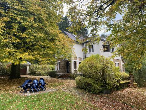 a white house with four chairs in front of it at Le Clos des Tilleuls - Gîte de Charme avec Piscine au Cœur de la Nature in Libin