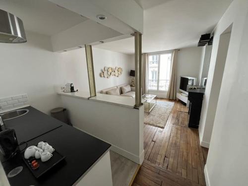 une cuisine avec un comptoir noir et un salon dans l'établissement Nid douillet Gare du Nord Montmartre Barbès, à Paris