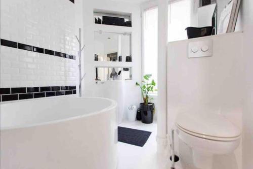 La salle de bains blanche est pourvue d'une baignoire et de toilettes. dans l'établissement Nid douillet Gare du Nord Montmartre Barbès, à Paris