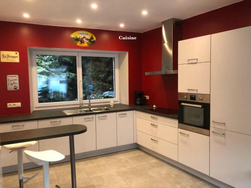 Una cocina con gabinetes blancos y una pared roja. en L'évasion, en Bouillon