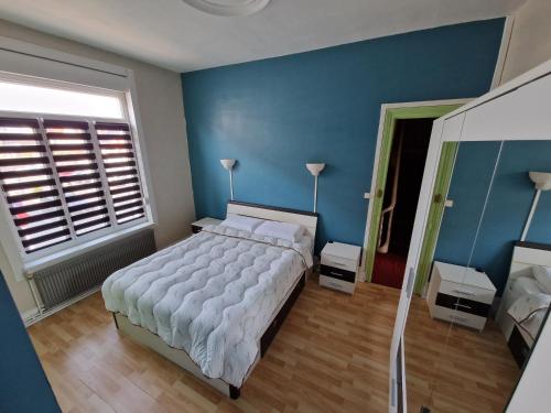 a bedroom with a large white bed and blue walls at Cœur de Saint-Pol in Dunkerque