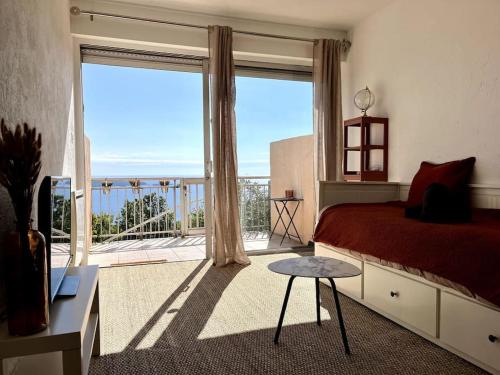 une chambre avec un lit et une grande fenêtre dans l'établissement Charmant studio avec terrasse privée et vue exceptionnelle, à Hyères