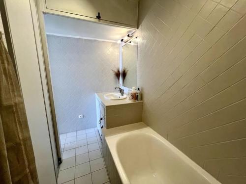 une salle de bain blanche avec une baignoire et un lavabo dans l'établissement Charmant studio avec terrasse privée et vue exceptionnelle, à Hyères