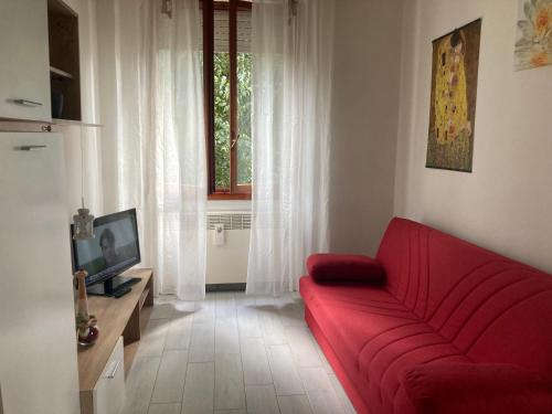 a living room with a red couch and a television at Casa Chiara tra Saronno e Milano in Saronno