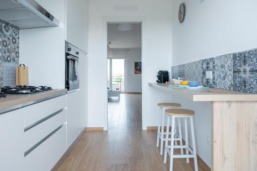 a kitchen with white cabinets and bar stools in it at House Of The Dragon in Acilia