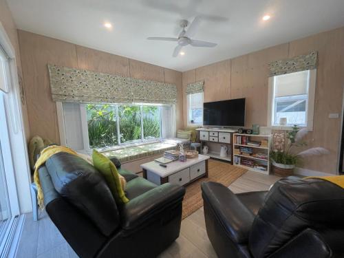 a living room with two leather chairs and a television at Downtown Mount Cottage in Mount Maunganui