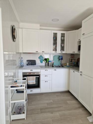 a white kitchen with white cabinets and a sink at Vivenda BRANCA in Carcavelos