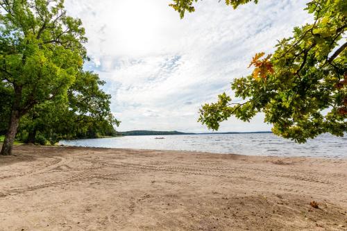 a sandy beach next to a body of water at Kallhällsbaden Strandhotell in Stockholm