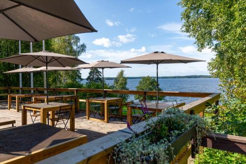 a patio with tables and umbrellas and a body of water at Kallhällsbaden Strandhotell in Stockholm