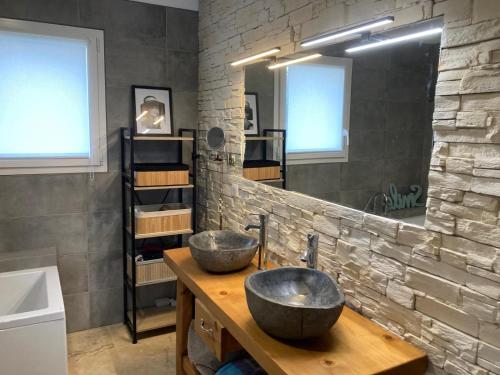 La salle de bains est pourvue de 2 lavabos et d'un mur en pierre. dans l'établissement Agréable et confortable maison Le Vigan en Quercy, au Vigan