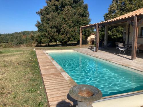 une piscine avec une terrasse en bois à côté d'une maison dans l'établissement Agréable et confortable maison Le Vigan en Quercy, au Vigan
