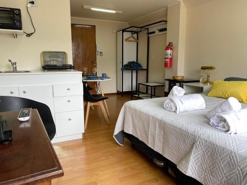 a bedroom with a bed with white sheets and a desk at Nido del Cormorán in Ushuaia