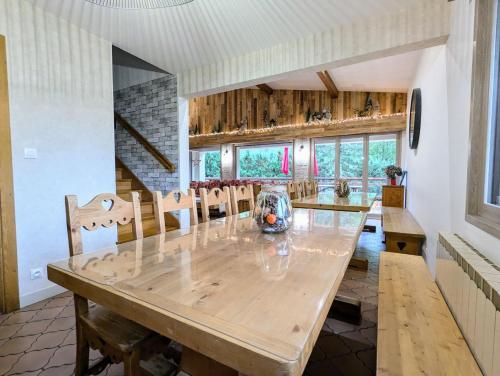 une salle à manger avec une grande table et des chaises en bois dans l'établissement LE VERTBRUCHE - Gîte avec superbe vue pour 15 pers, à La Bresse