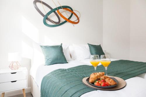 a bed with two glasses of wine and a plate of food at Opulent Residence - 1 BR Leicester City Centre in Leicester