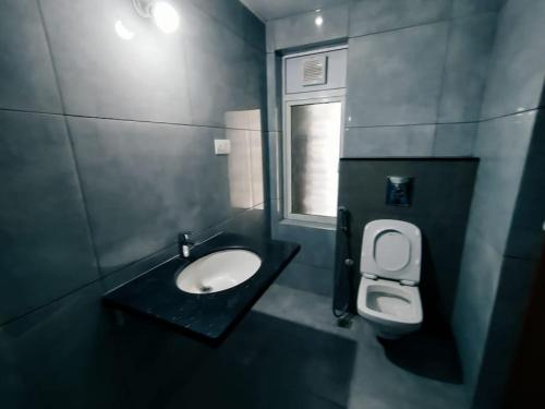 a bathroom with a sink and a toilet and a window at Skyline View Suite in Hyderabad