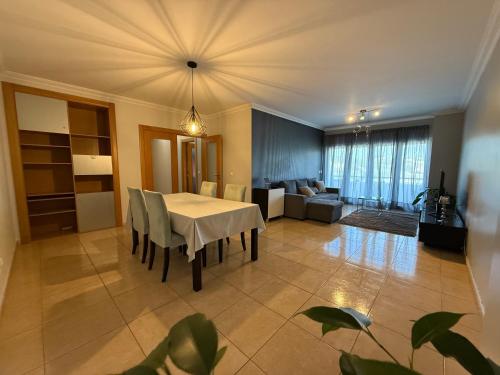 a dining room with a table and a living room at Casa de Férias Lucena in Lourinhã