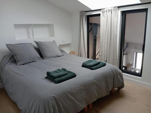 a bedroom with a bed with two green towels on it at Loft pays basque in Anglet